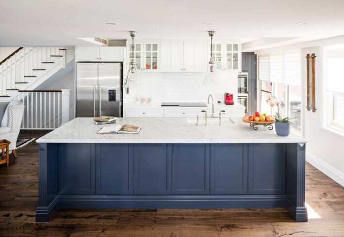 Hampton style kitchen with large white marble island bench top with navy panelling and a white subway tile splashback