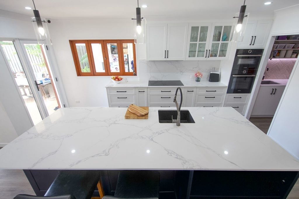 Top down view of white marble island bench and view to outside of kitchen