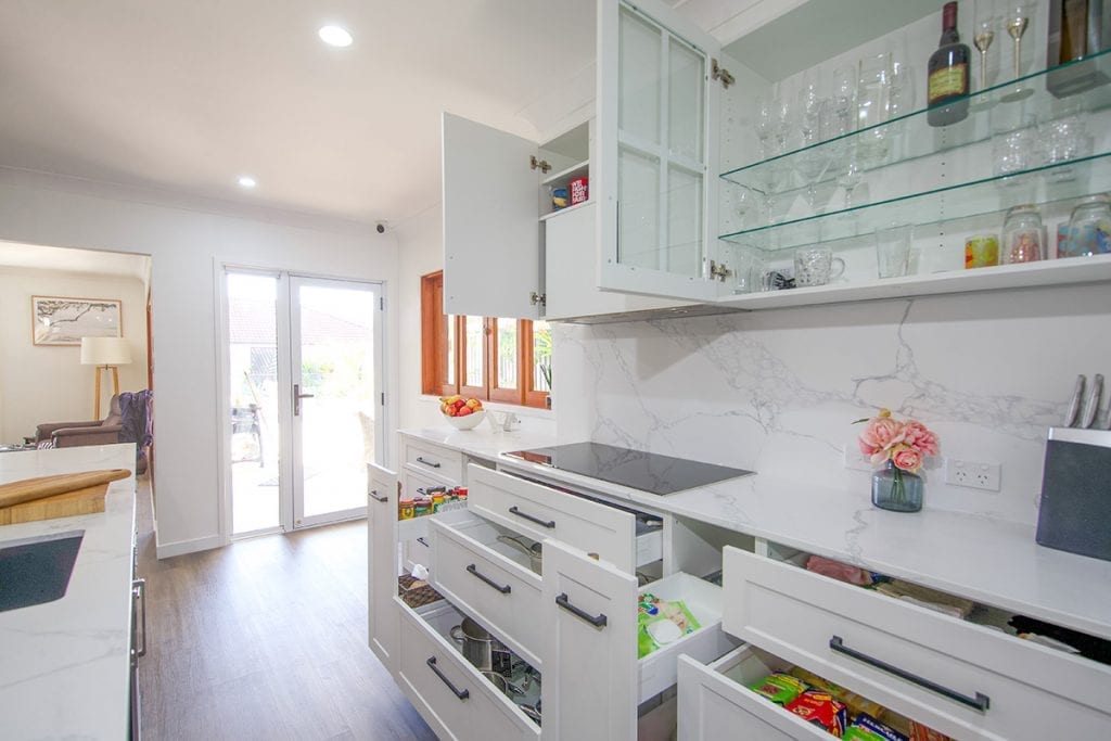 Open overhead kitchen cupboards for wine glasses with glass pane cupboard doors