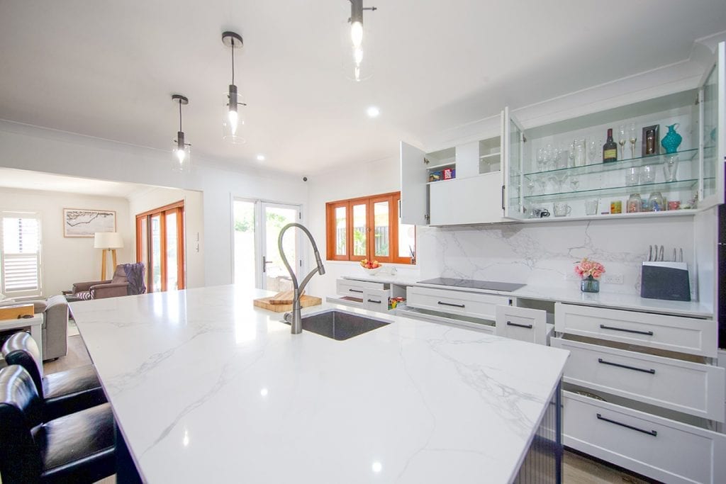 Large white marble Island Bench top under three clear glass hanging lights