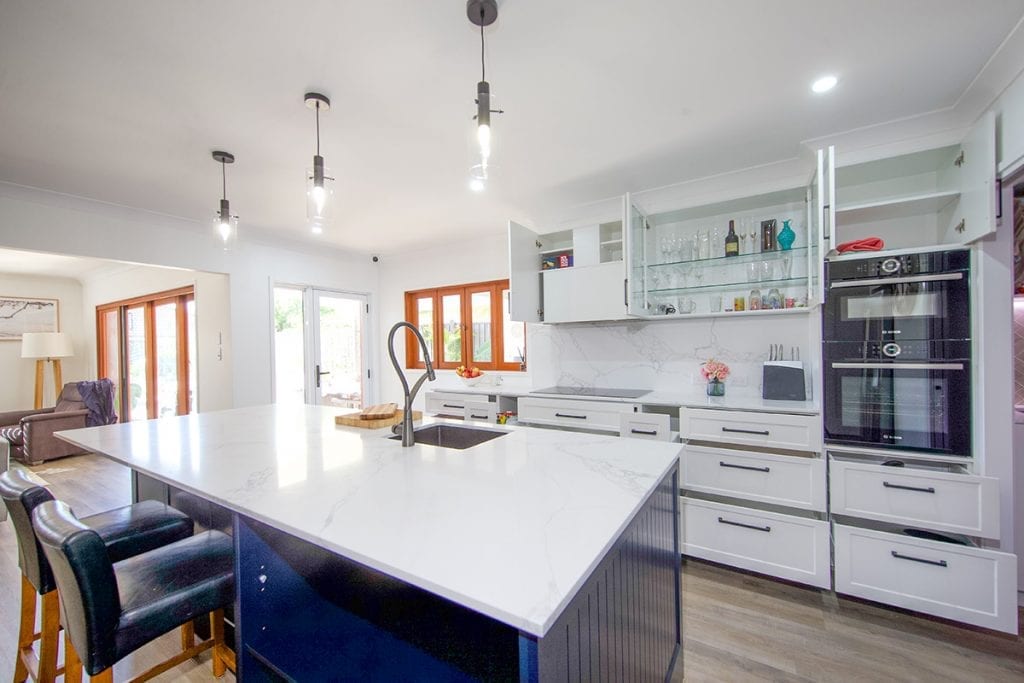 White marble island bench with blue timber pane walls and blue inset storage area