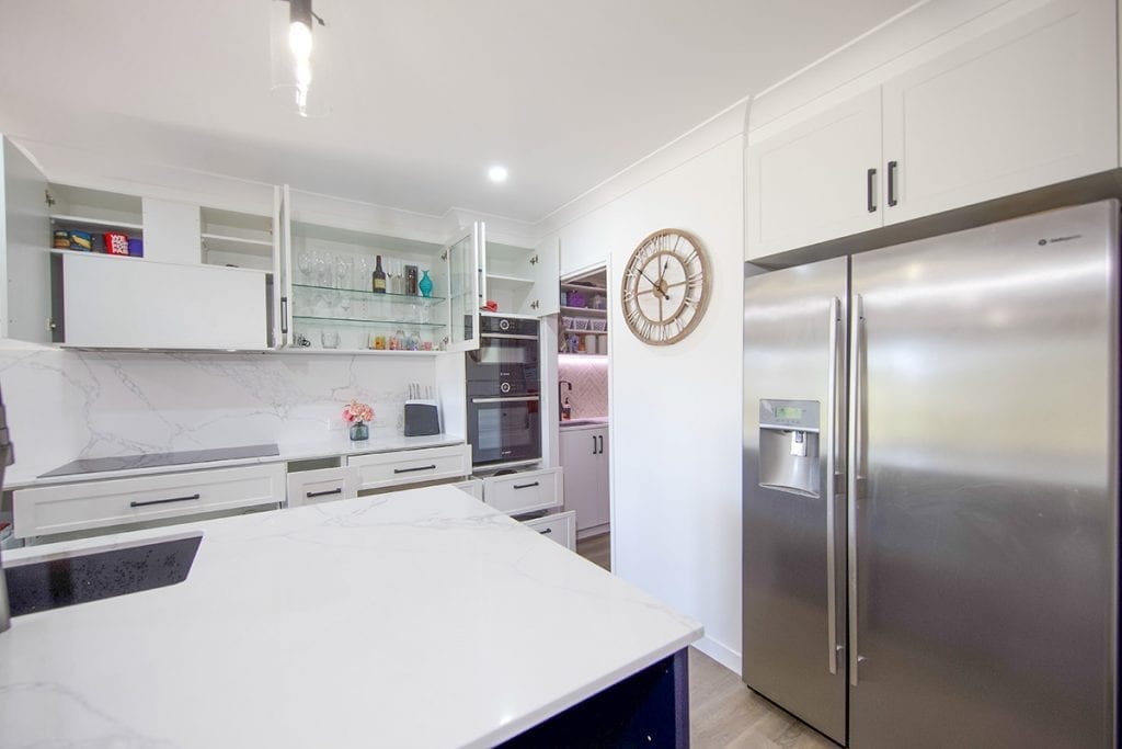 Double door stainless steel fridge and white island bench with basin