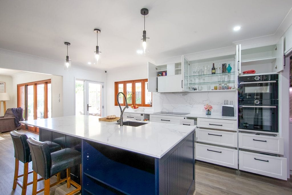 Wall mounted kitchen cupboards with inset black stove beneath overhead storage