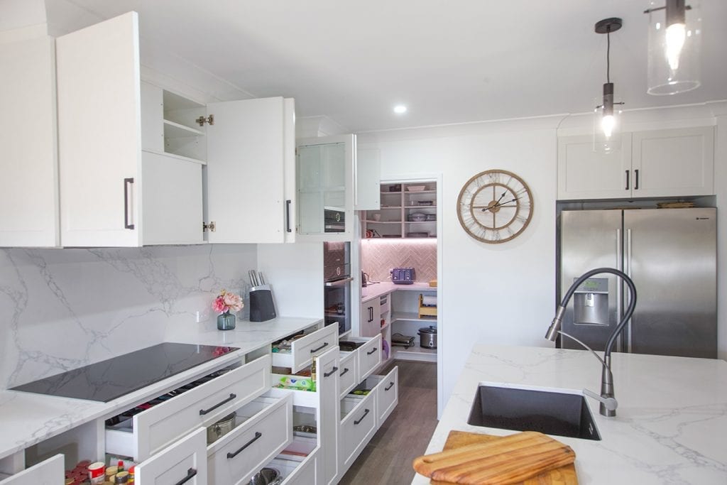 White kitchen cupboards above white marble splashback