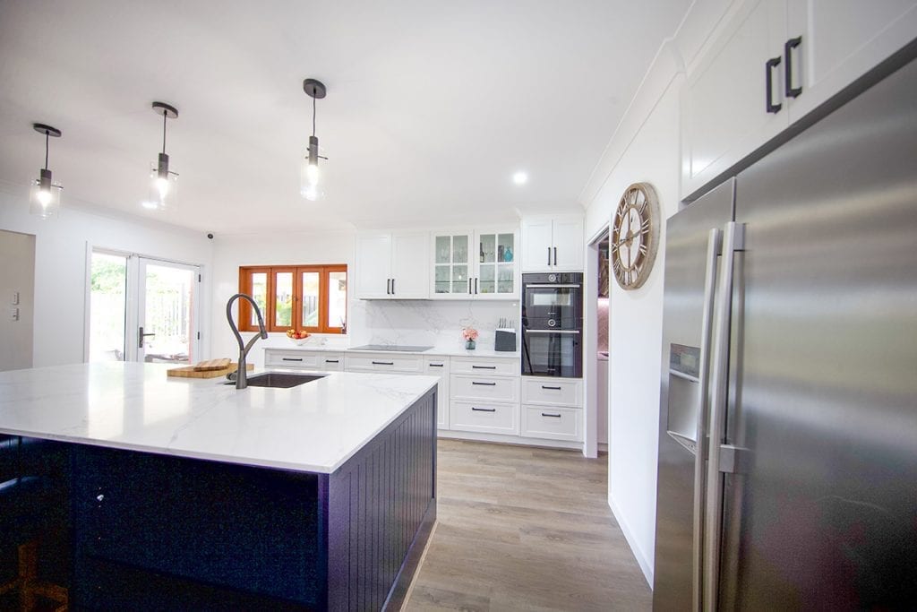 Double door stainless steel fridge next to blue island bench