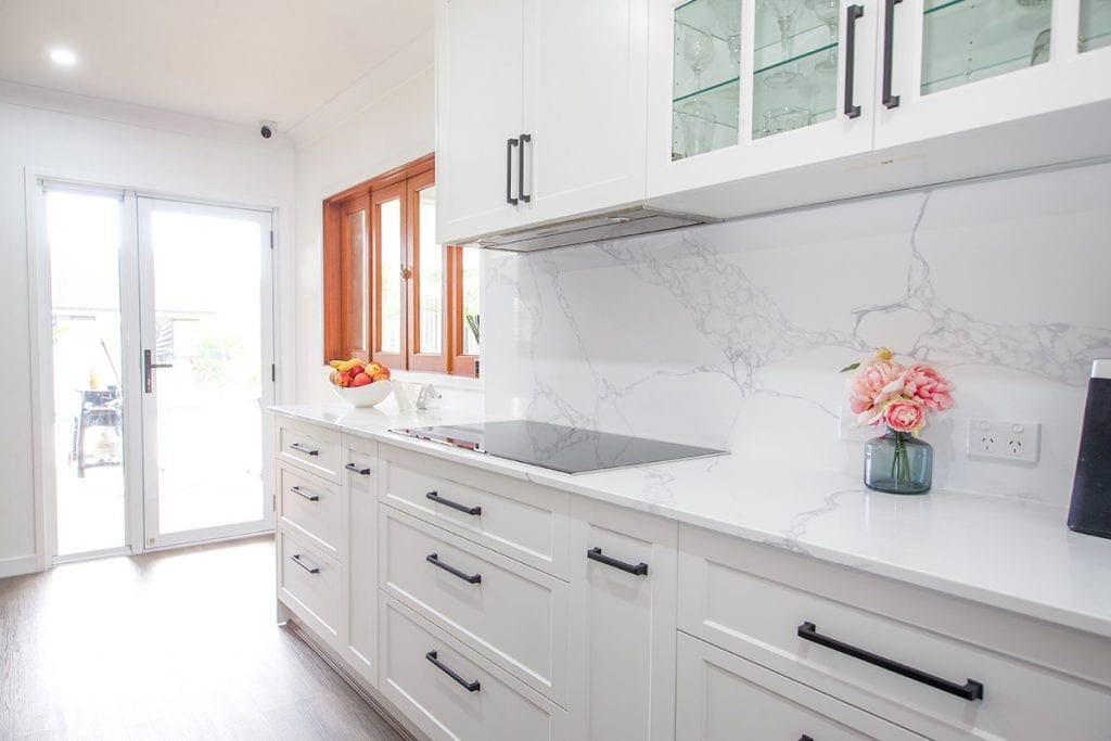 Clean white marble benches and white cabinets and storage drawers