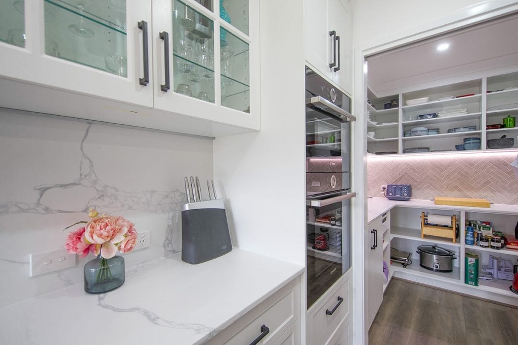 View of marble kitchen bench, wall inset stove and walk in pantry