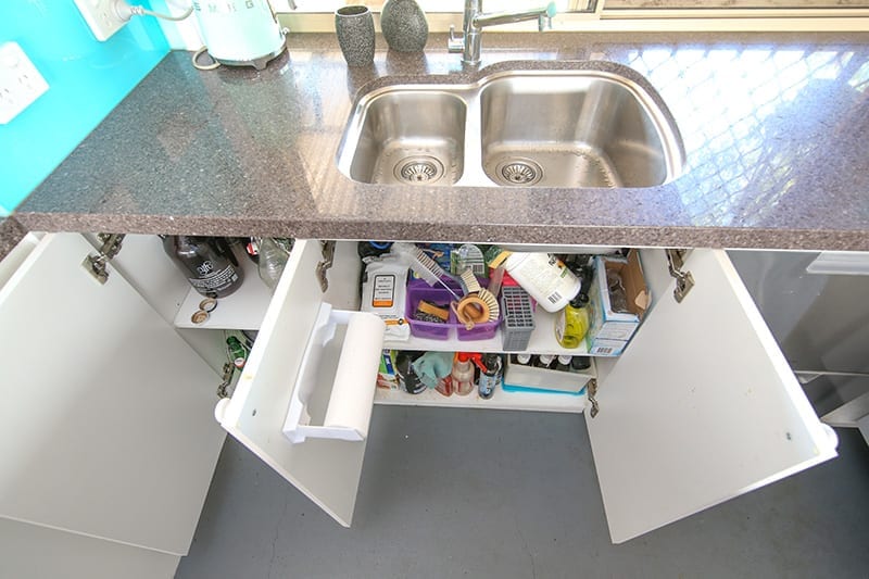 top down view of rounded stainless steel kitchen sink and cupboards under sink