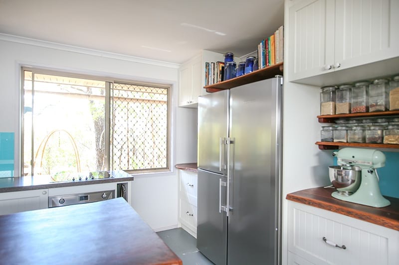three door stainless steel fridge and cake mixer on natural wooden bench tops