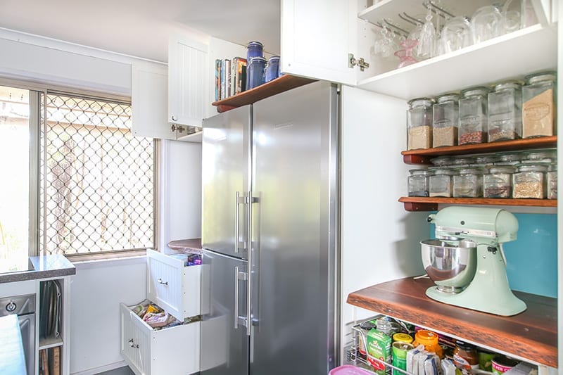 triple door stainless steel fridge surrounded by kitchen storage