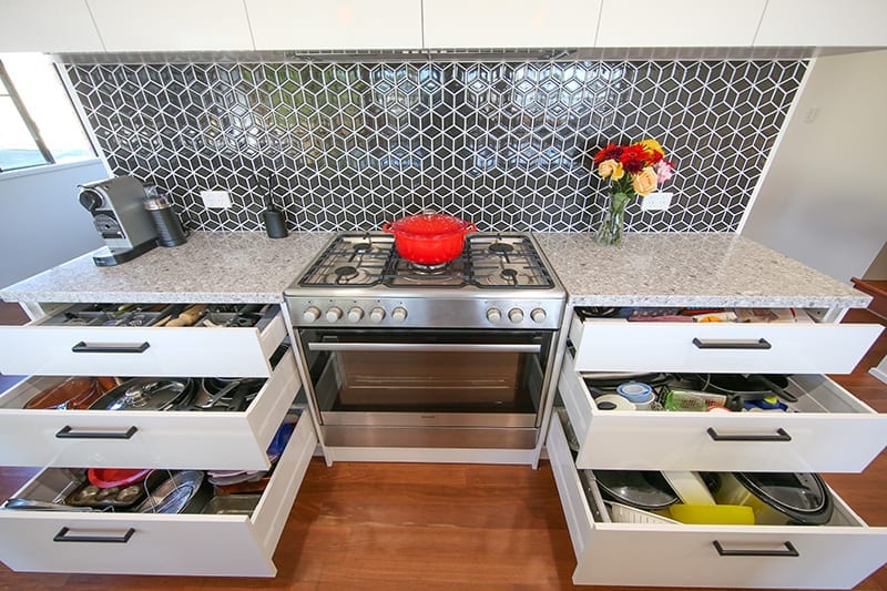 Open Sliding Kitchen Drawers for Pot and Pan Storage Beside Oven With Red Pot on Stove