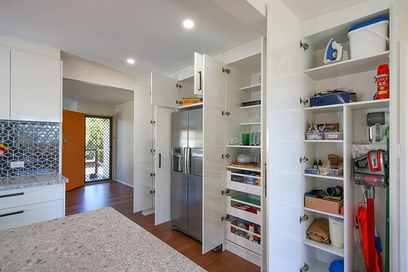 Open kitchen storage cupboards and broom closet for vacuum storage