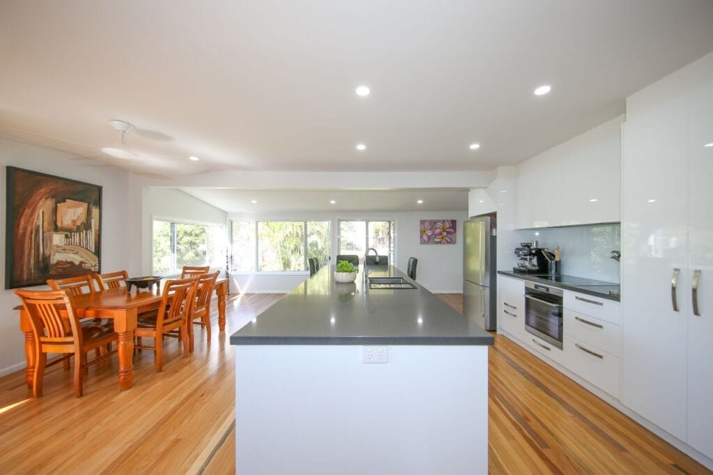 White Kitchen with Polished Wooden Floor and Dining Room Setting