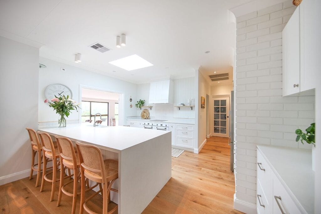 Hamptons Style Kitchen Setting with Barstools and Flower Vase