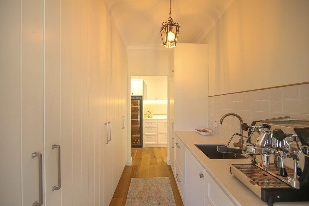 View down kitchen corridor with cupboards, coffee machine and hanging light