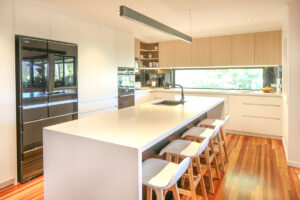 renovated kitchen with white waterfall island bench statement lighting and wooden floors