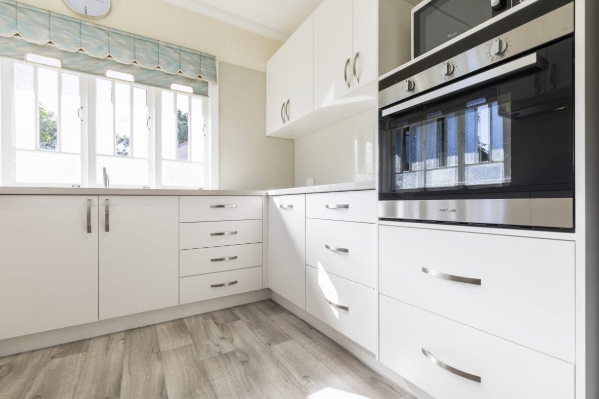 White modern country kitchen with silver handles and grey vinyl flooring