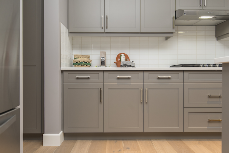 gold handle fixtures to grey shaker cabinet doors against white subway tile splashback